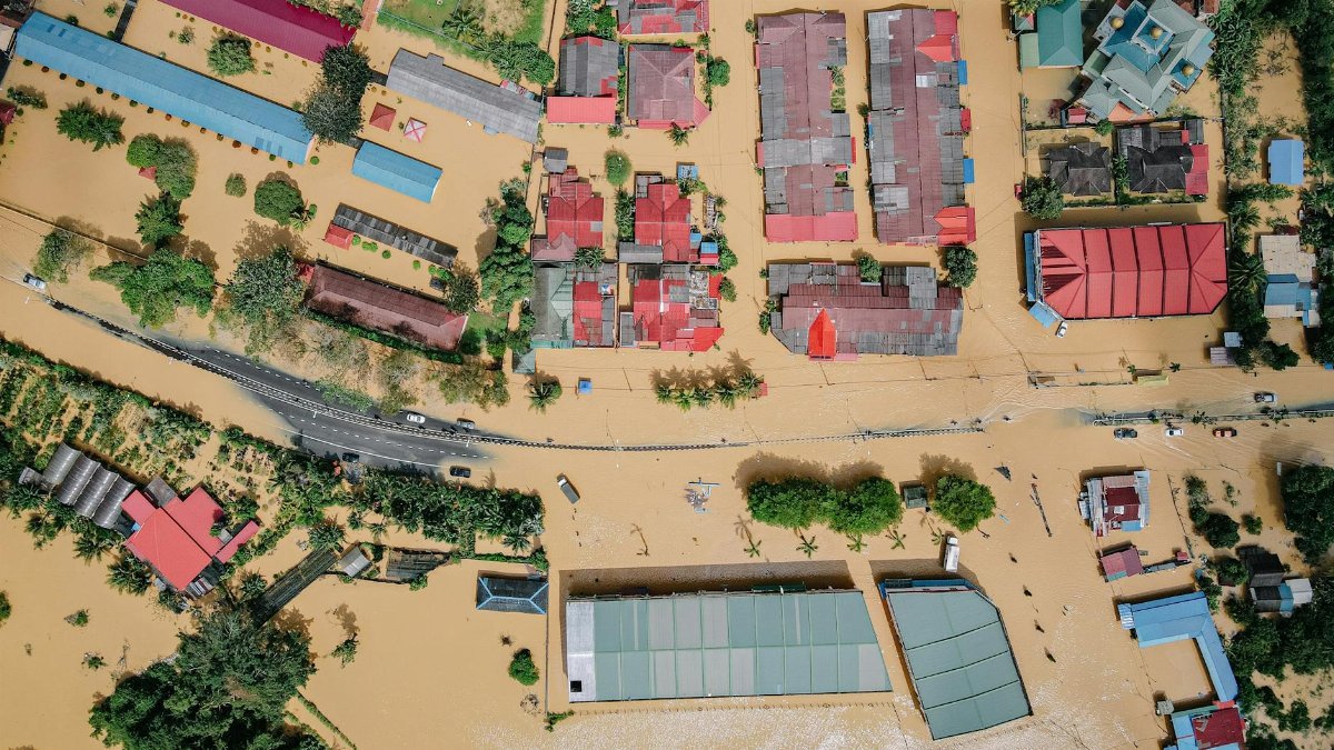 Aerial view showing significant flood damage in a residential neighborhood with inundated streets and homes.