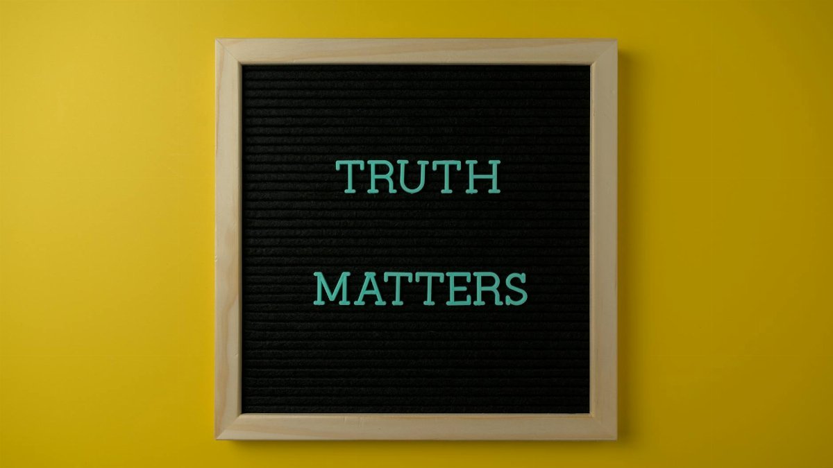 Close-up of black letter board with 'Truth Matters' message on yellow background.