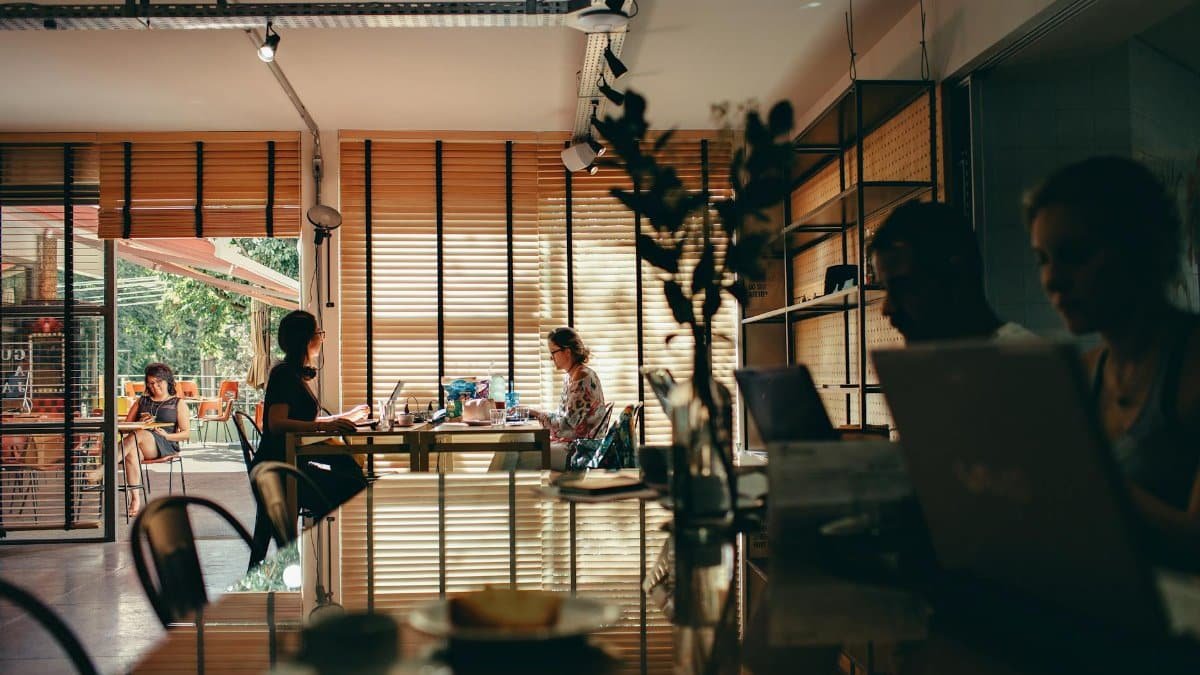 Interior of a bustling café with people working on laptops, creating a modern, collaborative atmosphere.