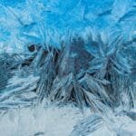 Close-up shot of delicate frost textures on a cold winter window, creating an abstract icy pattern.
