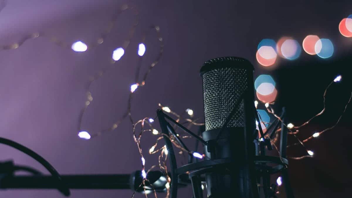 Condenser microphone surrounded by string lights creating a bokeh effect, ideal for studio and music themes.