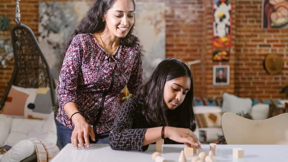 A mother and daughter enjoy creative play with wooden blocks in a cozy home setting.