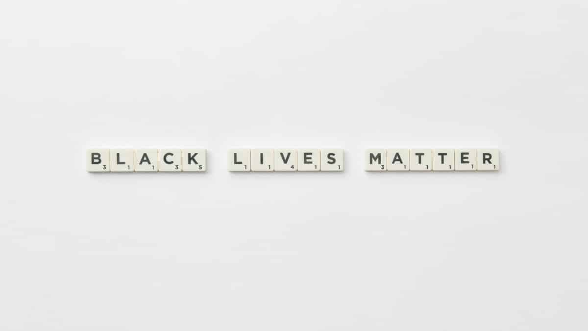Scrabble letter tiles spelling Black Lives Matter on a white background, with ample copyspace.
