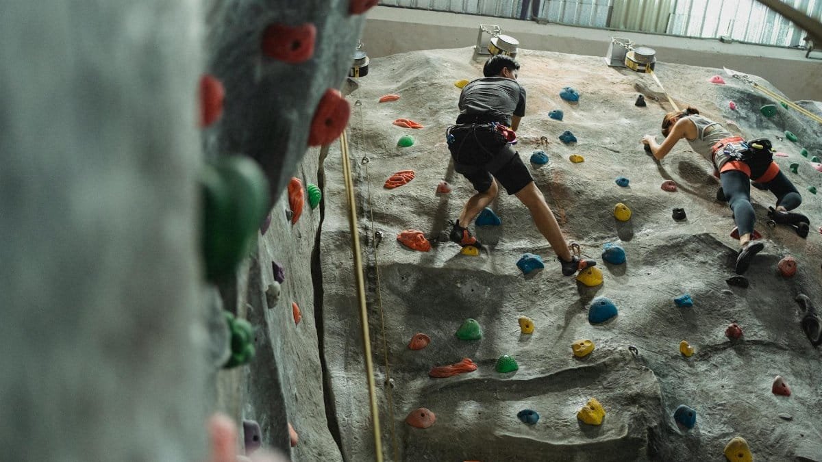 Two climbers tackle a challenging indoor rock climbing wall, emphasizing fitness and determination.