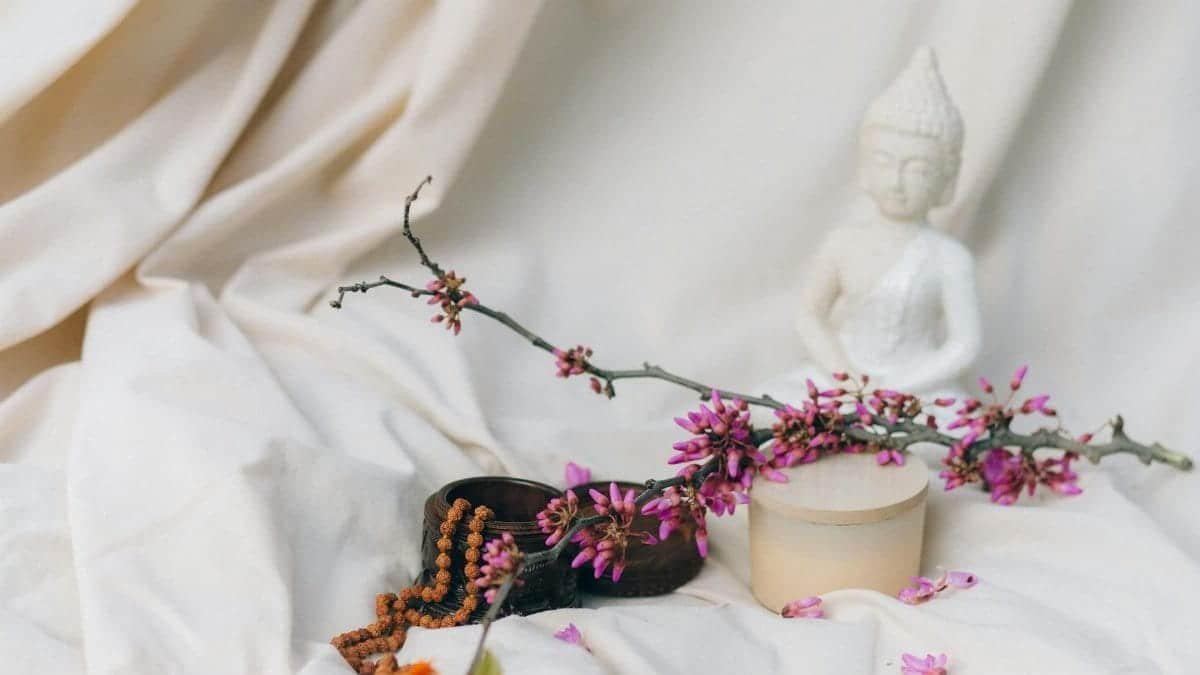 A tranquil setup with a Buddha statue, flowers, and meditation items, ideal for mindfulness and relaxation themes.