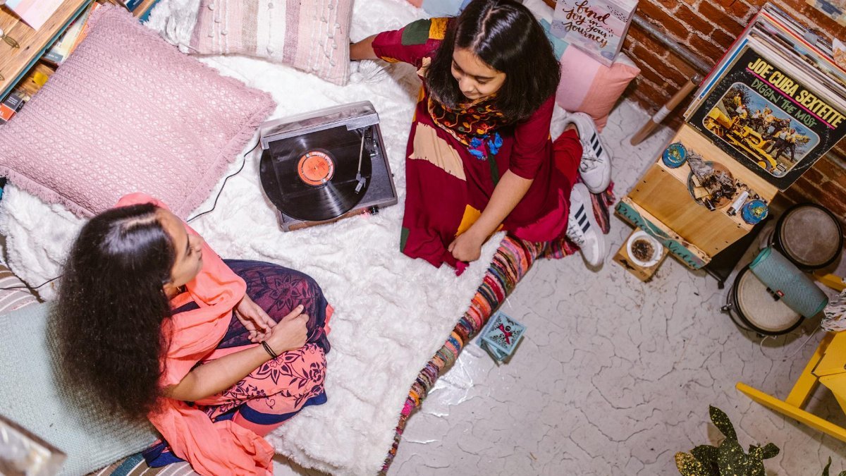 Two girls enjoying music on a vinyl record player indoors. Perfect for creative lifestyle themes.