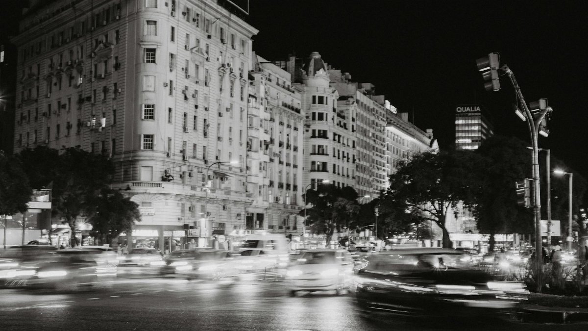 Black and white photo of bustling nighttime traffic in Buenos Aires, showcasing urban life and architecture.