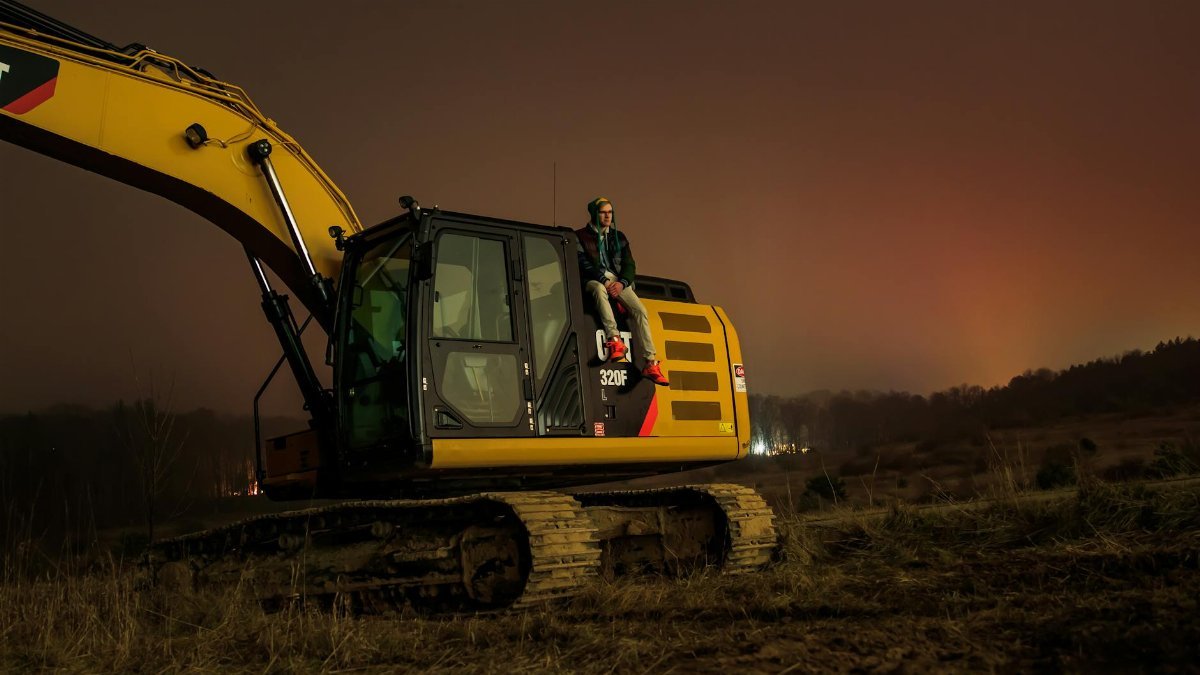 A person sitting on an excavator during the night in Greenville, Michigan. Tranquil rural setting.