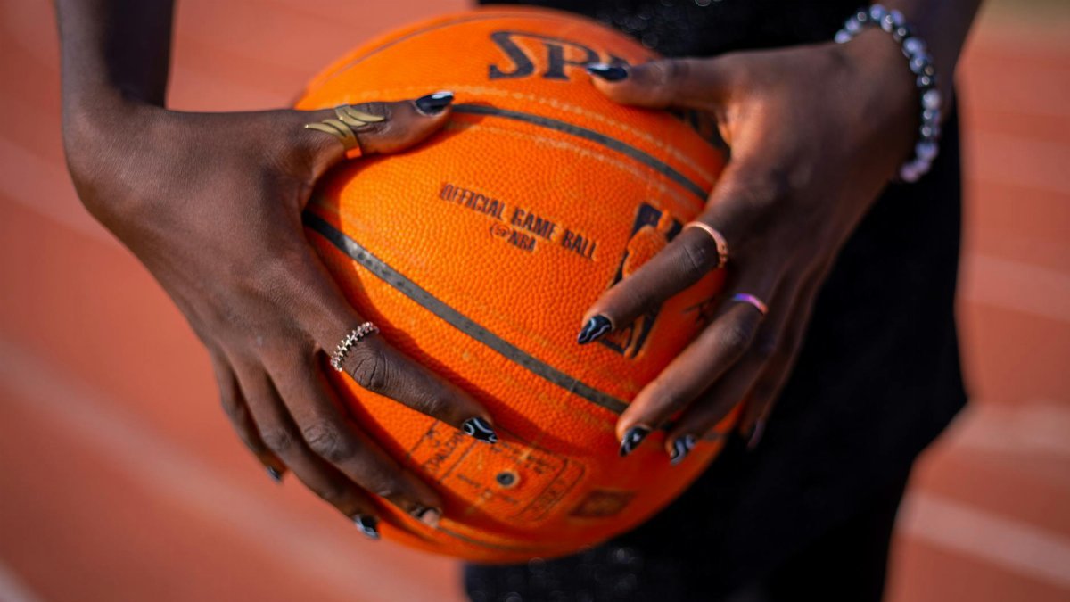 Close-up shot of hands holding a basketball on an outdoor sports track.