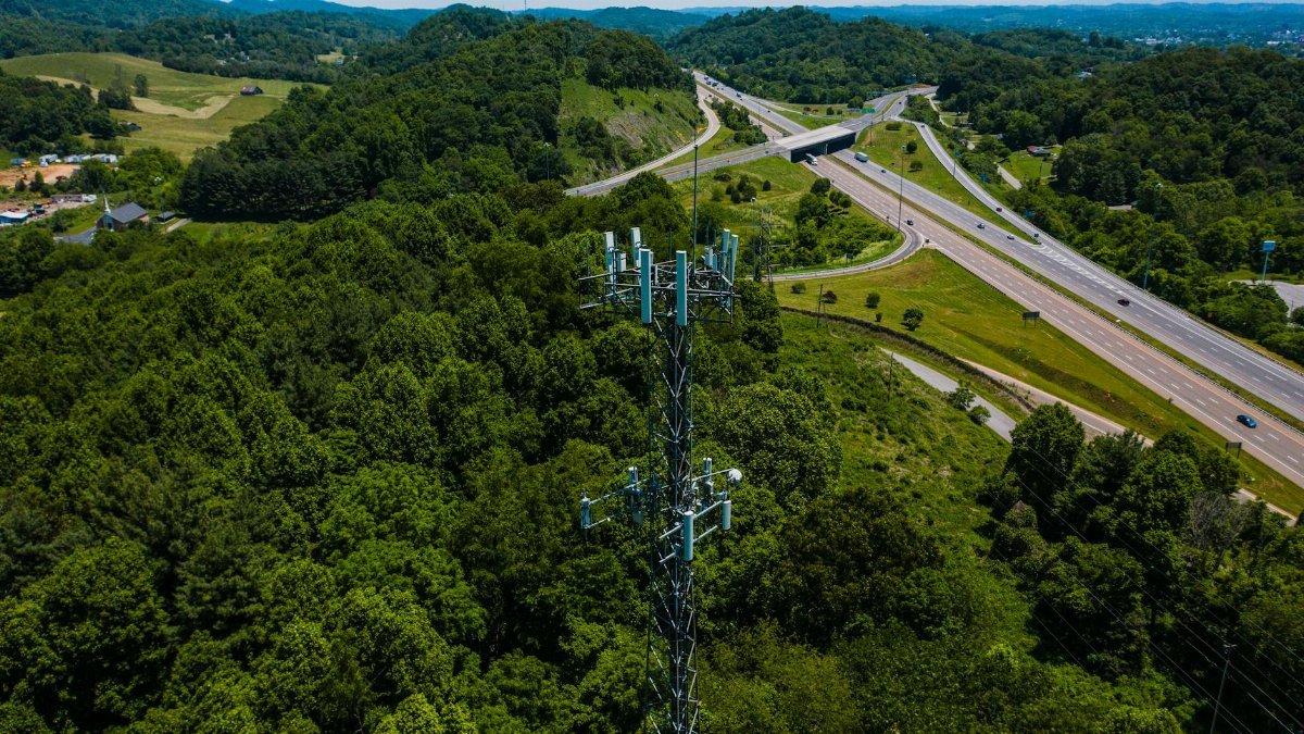 Aerial photo of a communication tower in lush forested landscape alongside highway in Virginia.