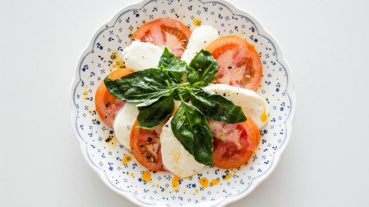 Fresh Caprese salad with tomatoes, mozzarella, and basil on a decorative plate.