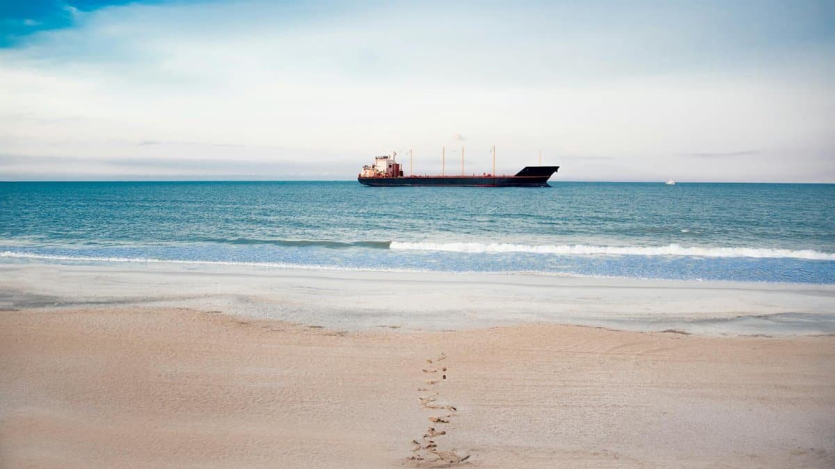 A tranquil beach scene with a cargo ship in St. Augustine, Florida, highlighting oceanic beauty and summer vibes.