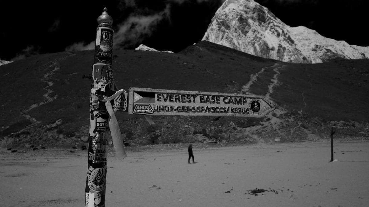 Directional sign leading to Everest Base Camp with mountains in monochrome setting.