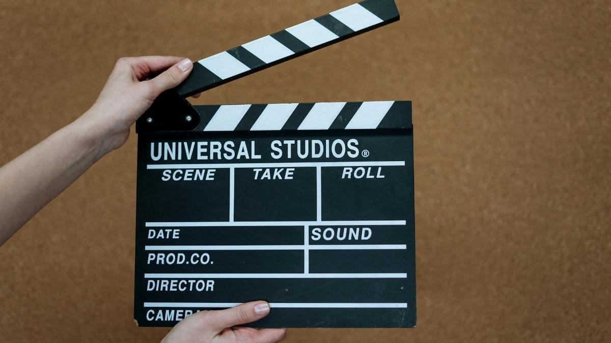 Close-up of Universal Studios clapboard on a cork background held by hands.
