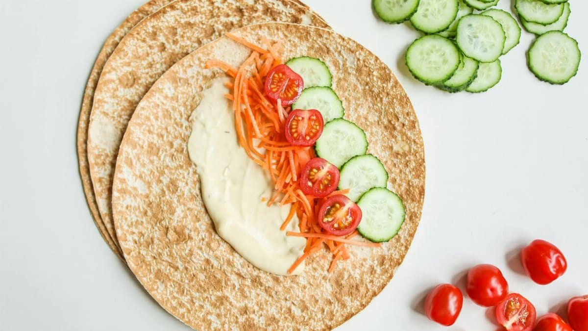 A healthy vegan wrap with fresh cucumbers, tomatoes, and carrots on whole wheat pita.