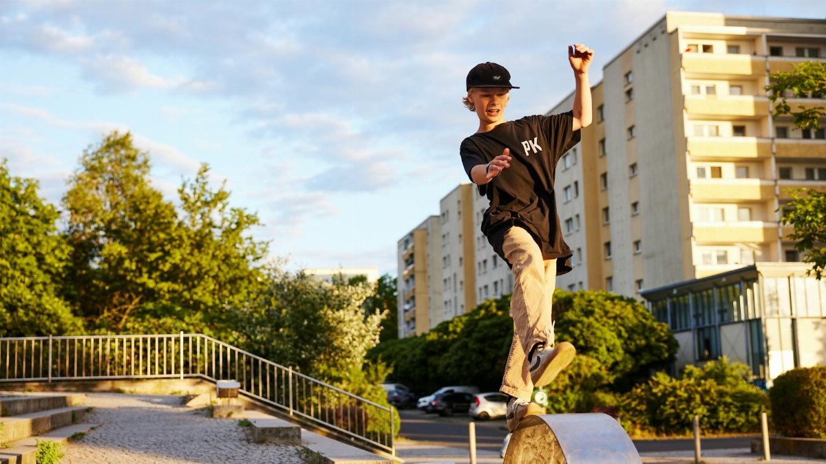 A teenager skillfully skateboarding on a ramp in a city park during the day.