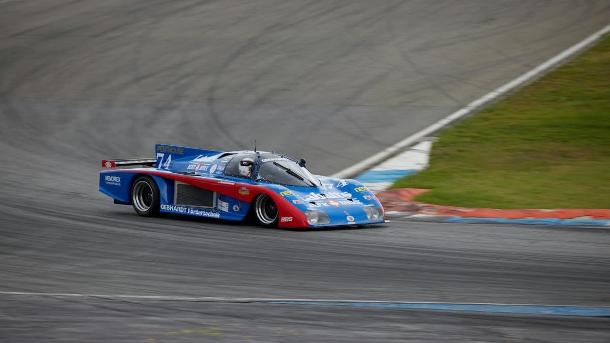 A blue vintage race car speeds through a turn at Hockenheim's iconic racetrack.