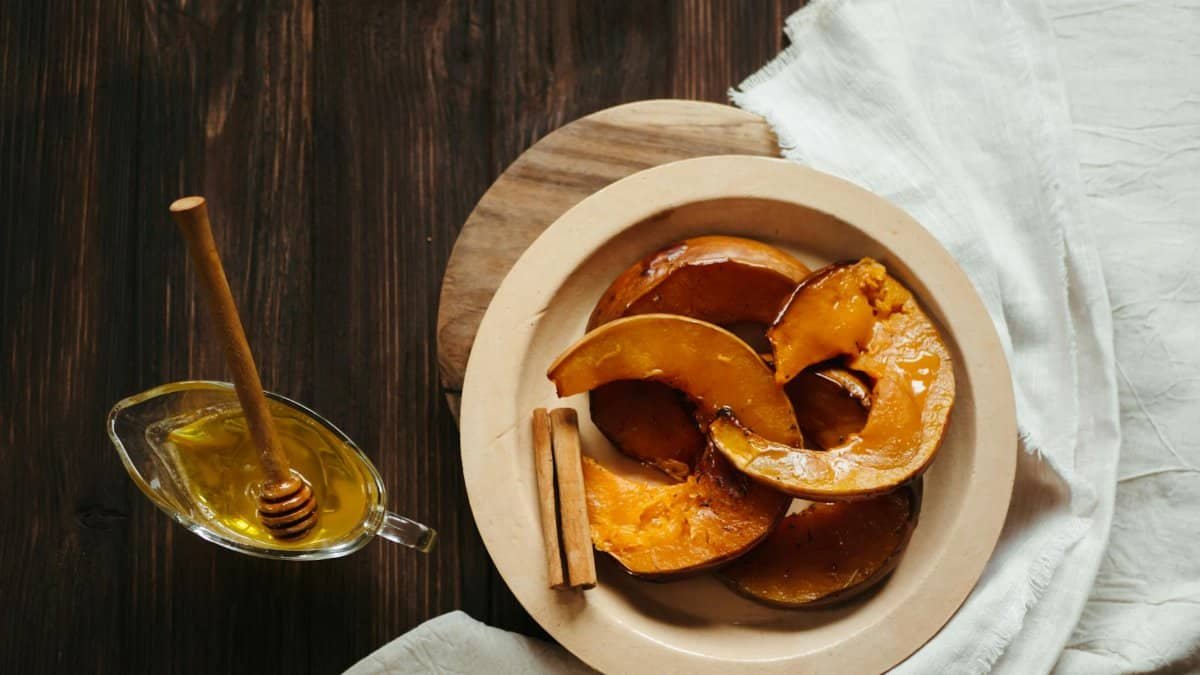 Delicious baked pumpkin slices with honey and cinnamon on a rustic wooden table.