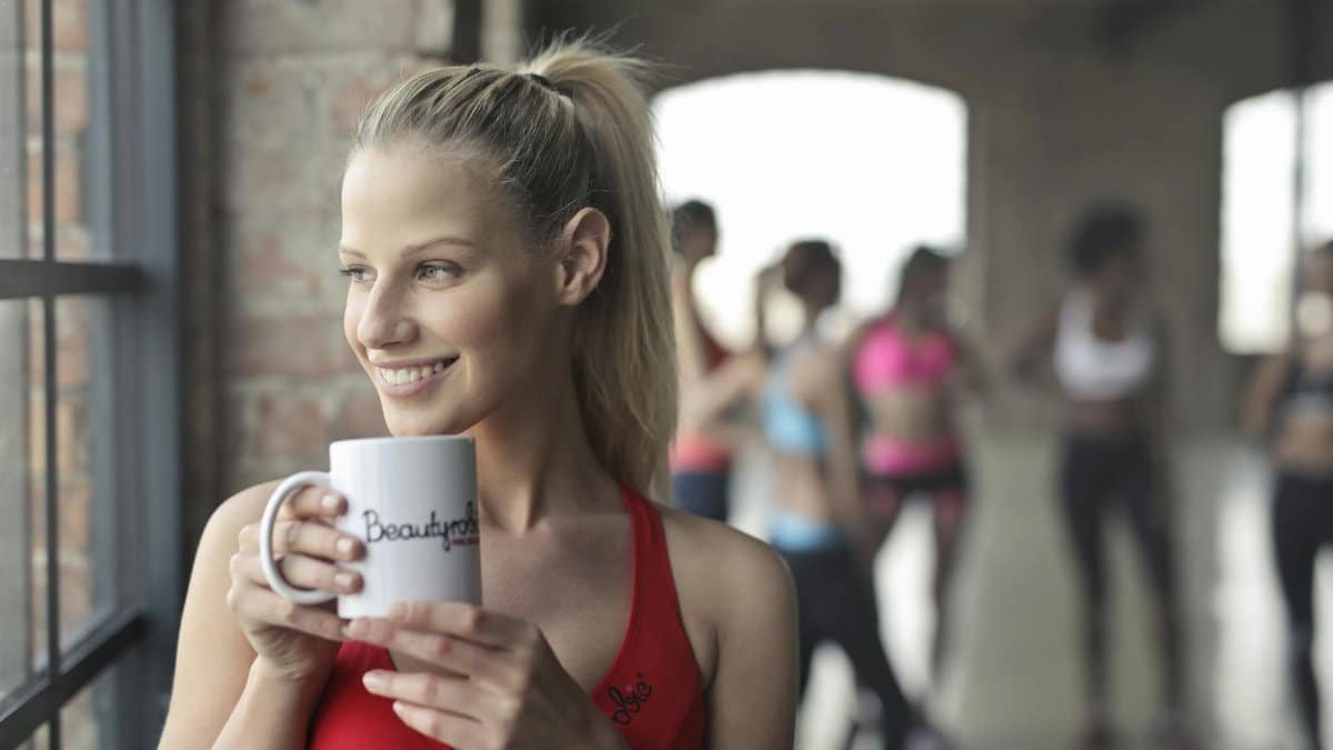 Woman in activewear enjoying a coffee break indoors at a gym in Budapest.