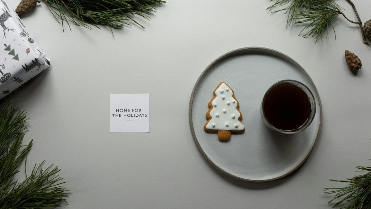 Holiday setup with gingerbread cookies, coffee, pine branches, and a gift card.