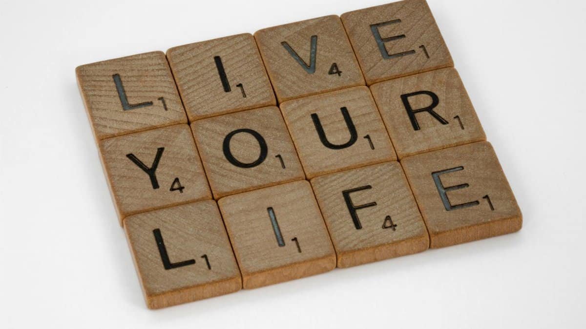 Scrabble tiles form the phrase 'Live Your Life' on a white background.