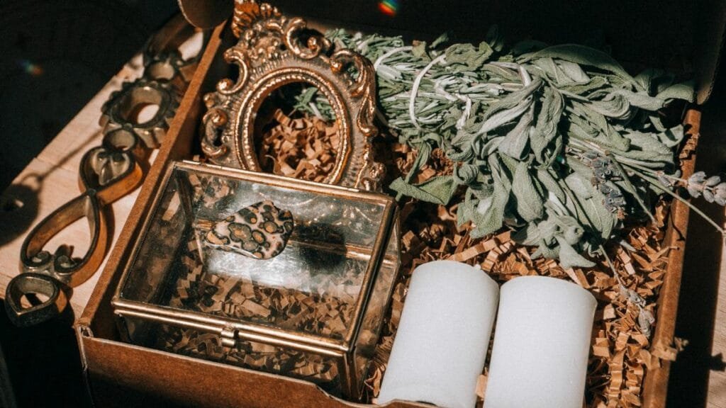 A beautifully arranged gift box containing sage, candles, and decorative items.