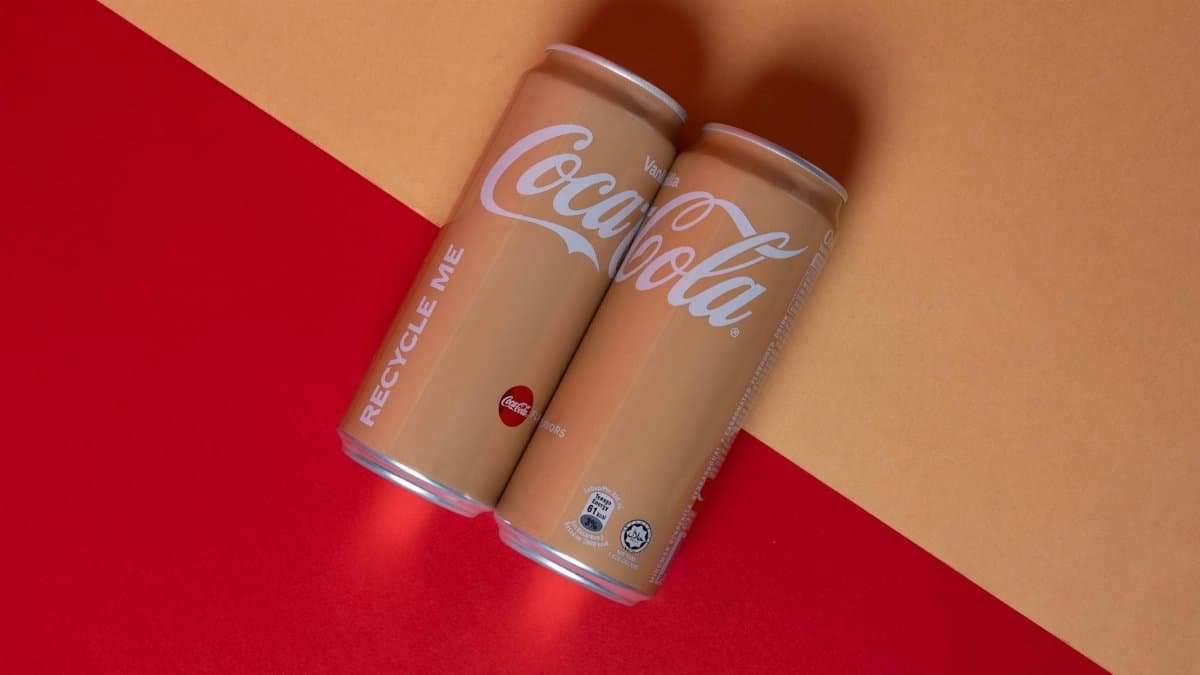Studio shot of Vanilla Coca-Cola cans on vibrant red and yellow background.