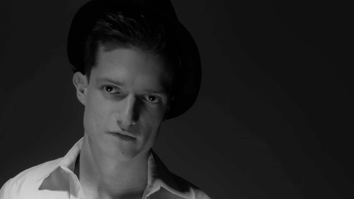 Black and white portrait of a contemplative man wearing a hat, exuding mystery.