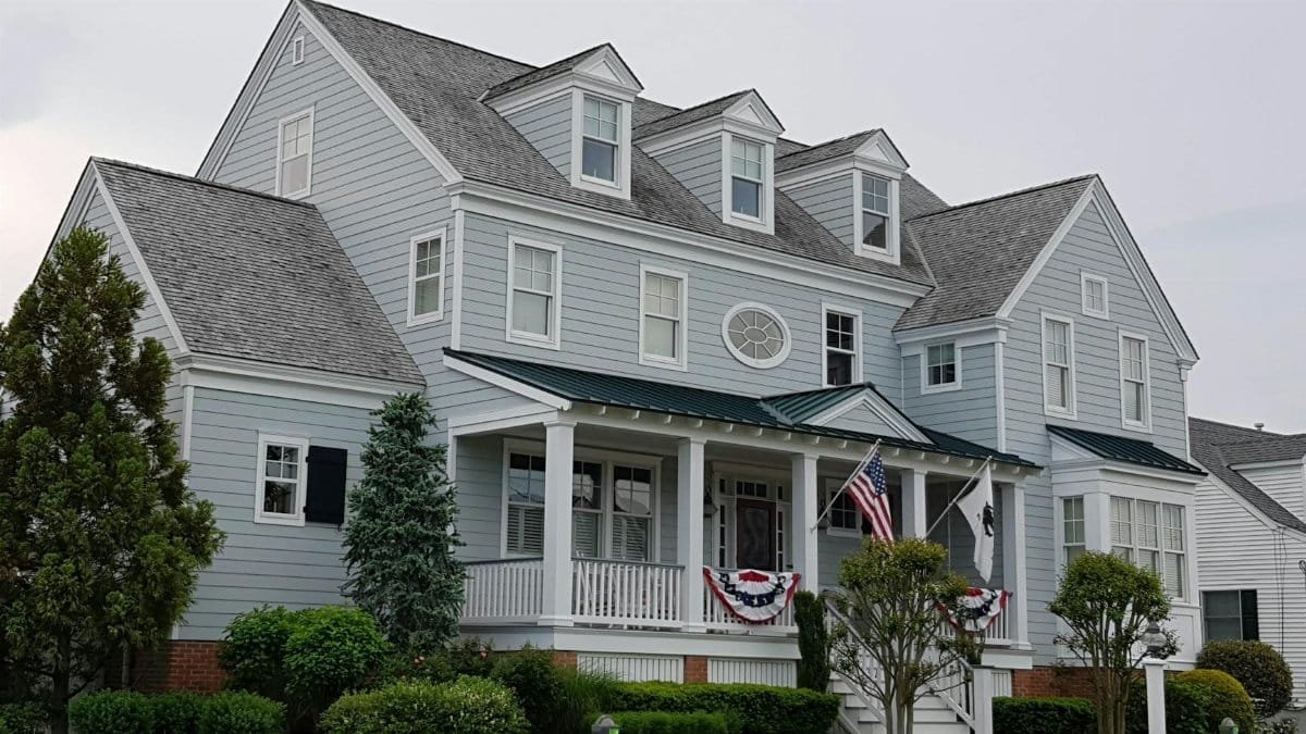 Elegant colonial-style house in Cape May, NJ with manicured lawn and American flags.