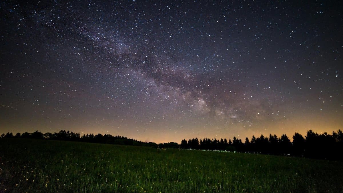 A breathtaking view of a starry night sky over a quiet field, showcasing the Milky Way.