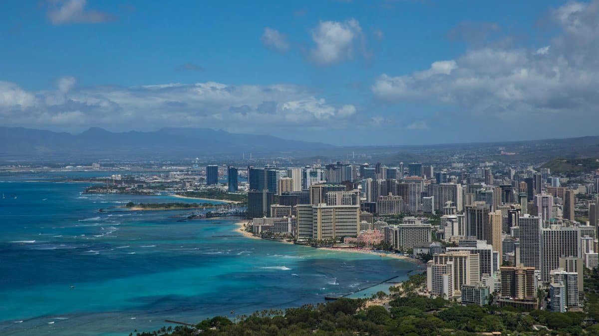 Stunning aerial view of Honolulu's skyline with vibrant ocean hues and lush greenery.