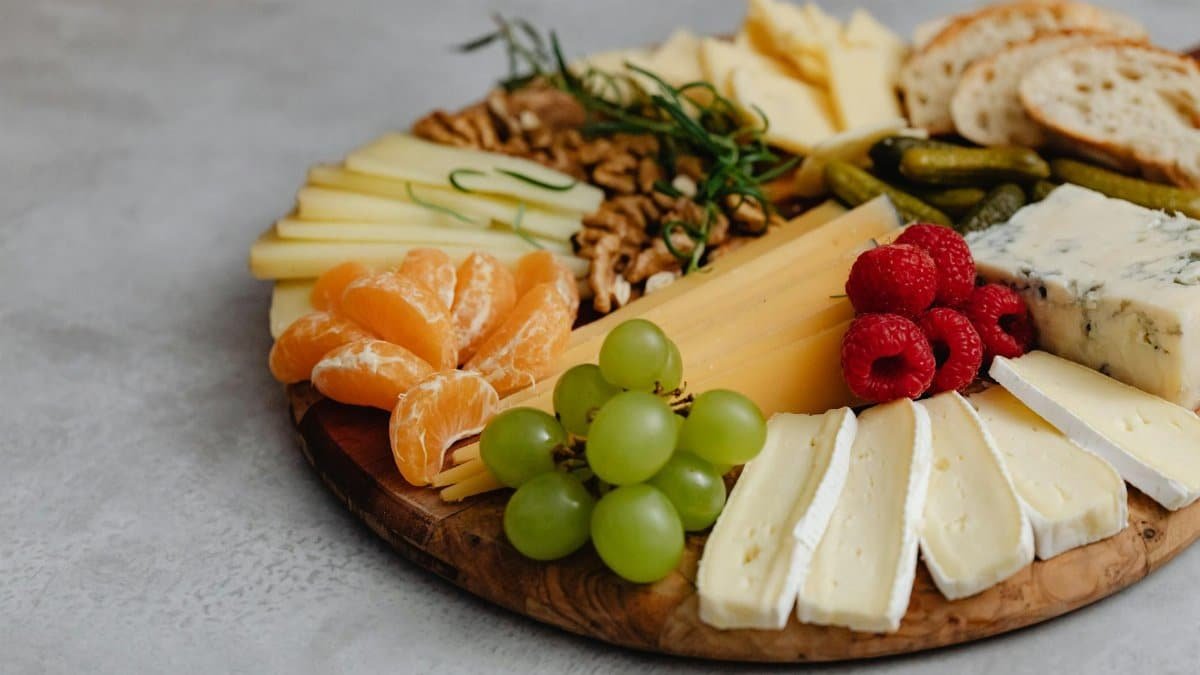 A visually appealing cheese platter with an assortment of fruits, nuts, and crackers.