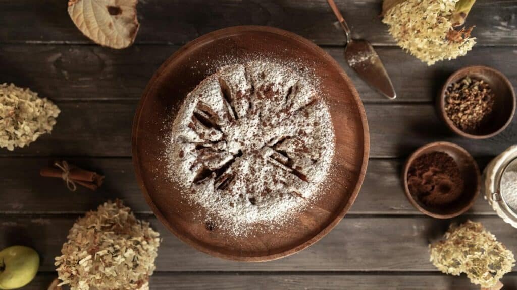 Overhead view of a cake dusted with powdered sugar surrounded by natural elements.