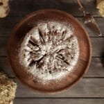 Overhead view of a cake dusted with powdered sugar surrounded by natural elements.