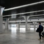 A man with luggage walking through a spacious, modern, empty airport hall.