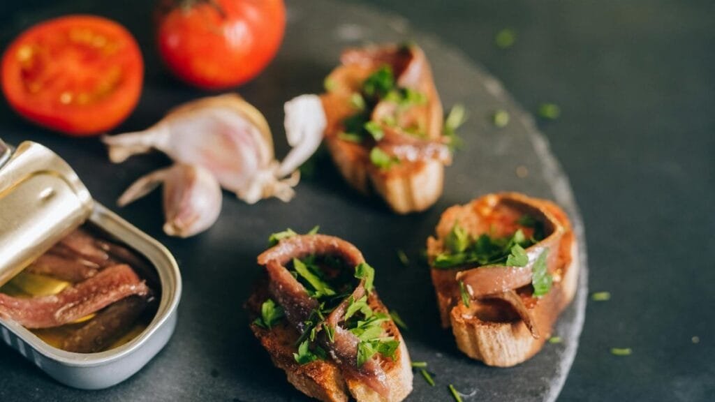 Mouth-watering bruschetta topped with anchovies and fresh herbs, paired with tomatoes and garlic.