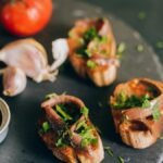 Mouth-watering bruschetta topped with anchovies and fresh herbs, paired with tomatoes and garlic.