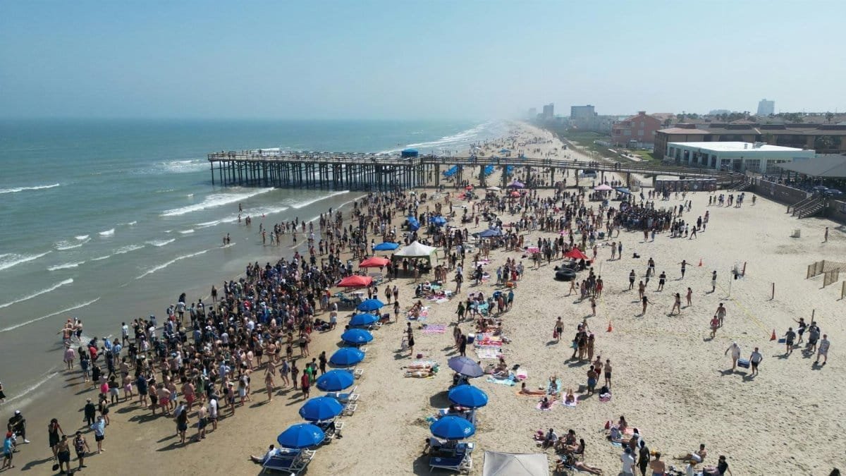 Lively beach scene at South Padre Island, Texas with crowds enjoying the sunny day.