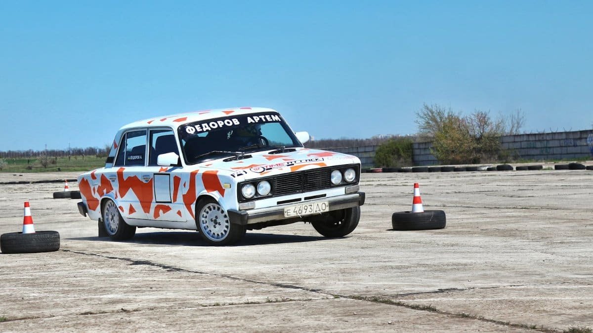 A decorated car navigates an outdoor obstacle course marked with traffic cones.
