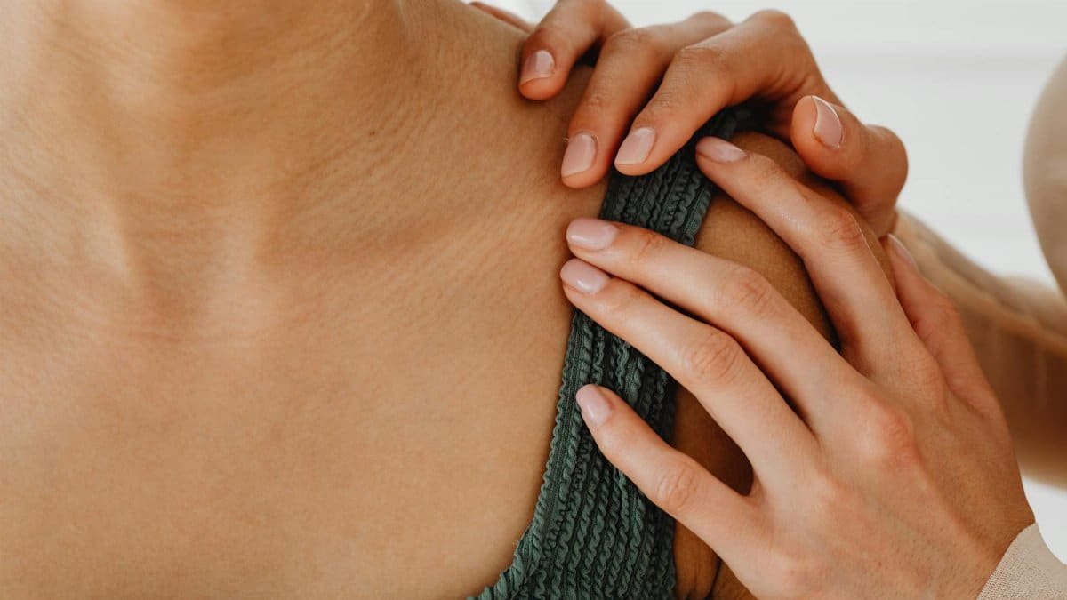 A close-up of hands gently resting on a shoulder, conveying care and comfort.