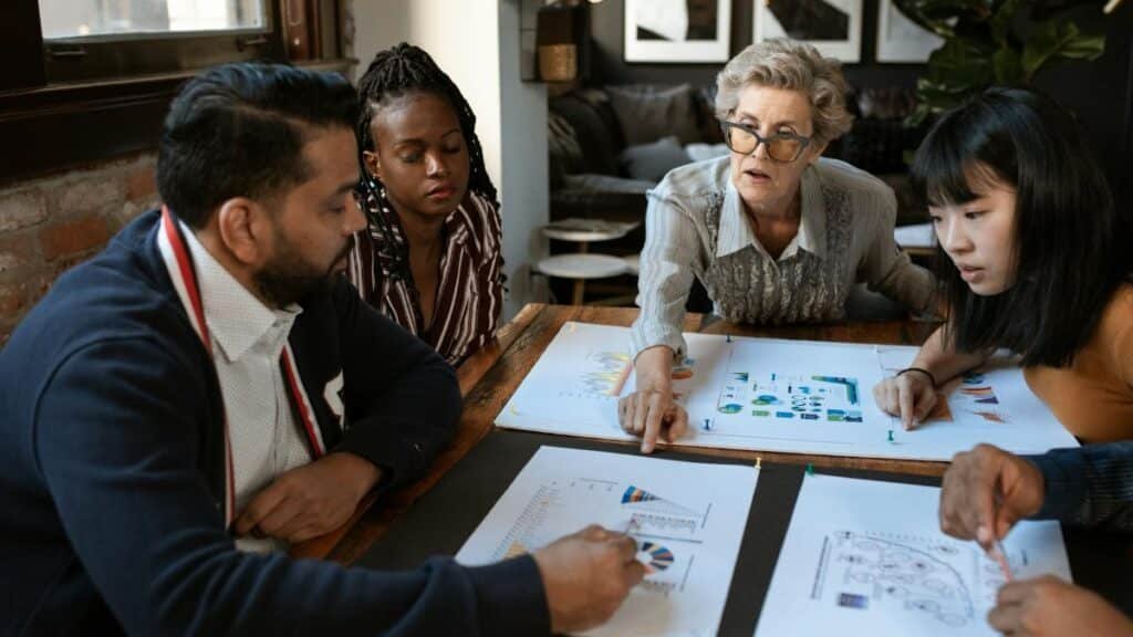 A diverse group of professionals brainstorming over charts in a stylish office setting.