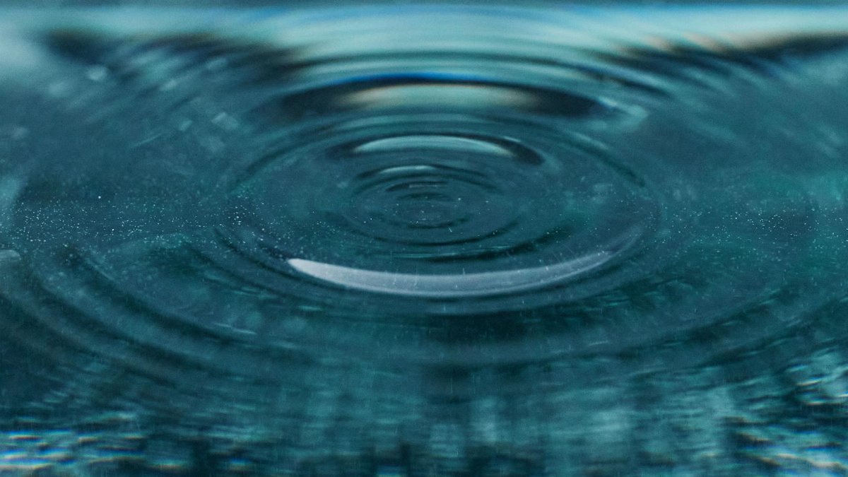 Beautiful detailed view of a ripple expanding on a blue water surface, capturing texture and motion.