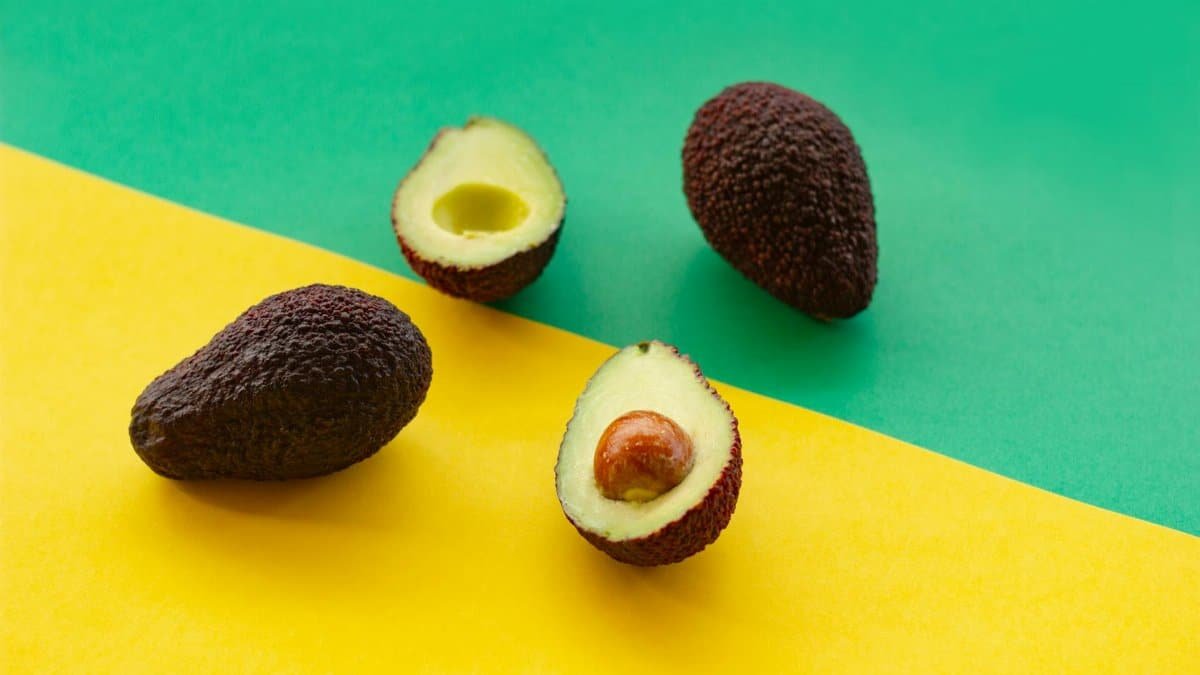 Ripe avocados displayed on vibrant green and yellow background, perfect for culinary themes.