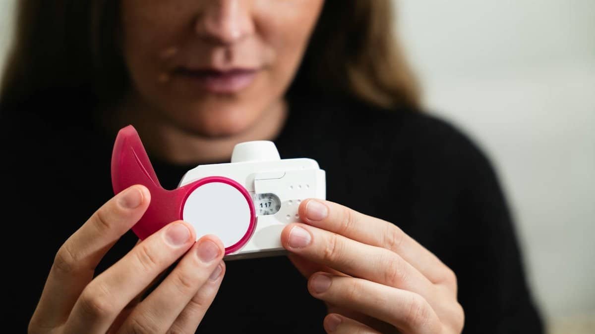 Close-up of a woman holding a medical inhaler device for respiratory conditions.