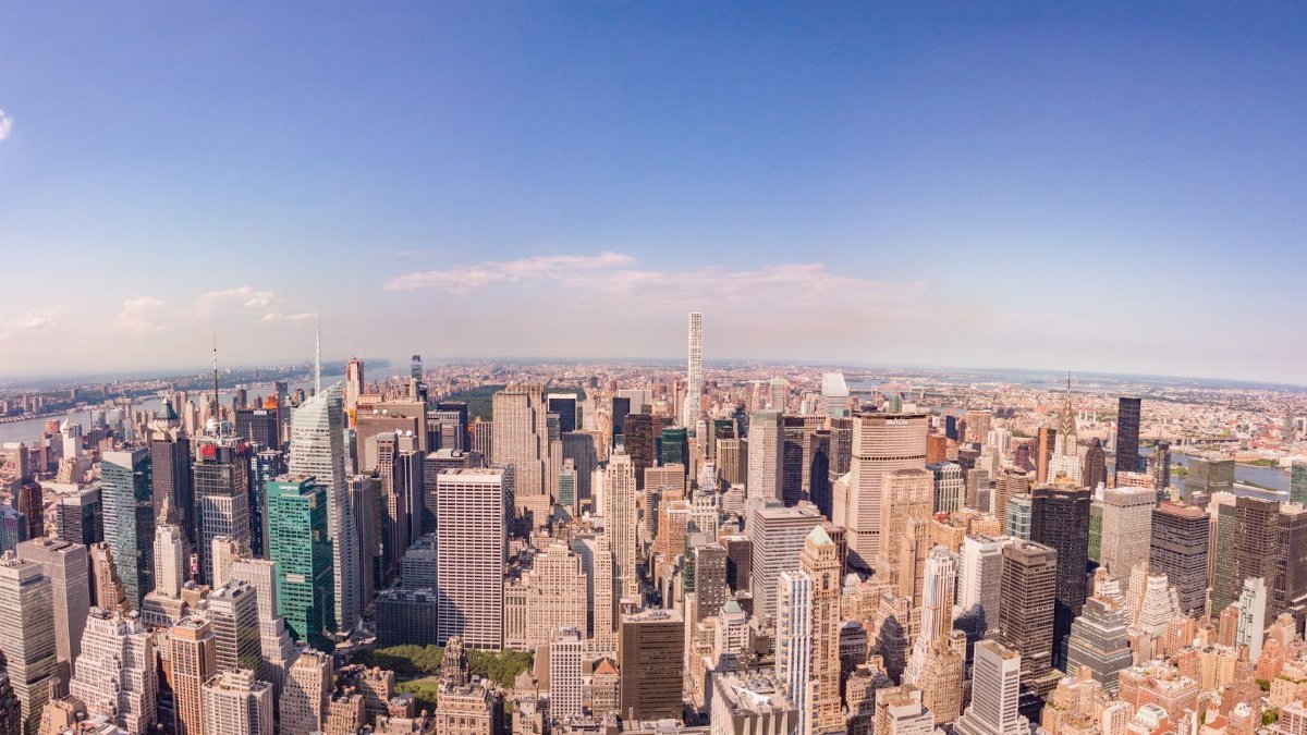 Panoramic aerial view of the iconic New York City skyline featuring skyscrapers and the Hudson River.