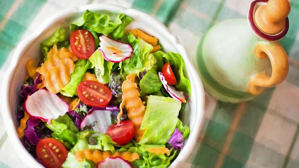 Colorful fresh vegetable salad with cherry tomatoes in a white bowl.