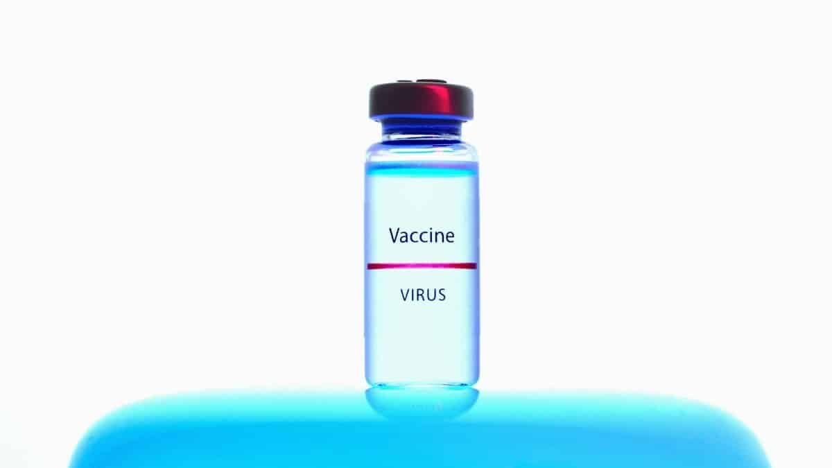 Close-up of a vaccine vial against a bright blue background, symbolizing medical research.