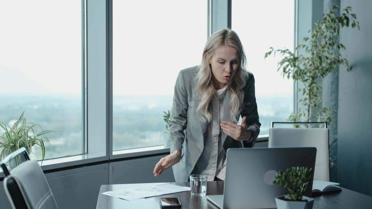 Businesswoman engaging in a video call, demonstrating leadership in a modern office setting.
