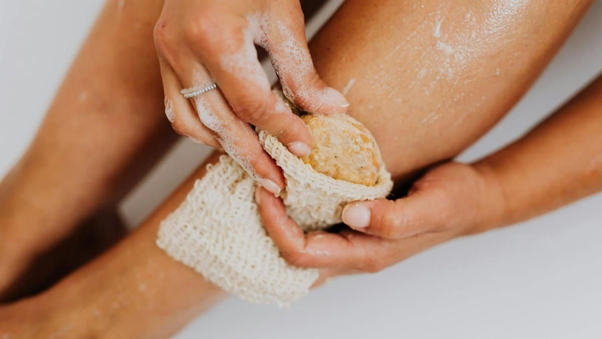 Detailed view of a person exfoliating their leg with a natural loofah sponge for skin care.