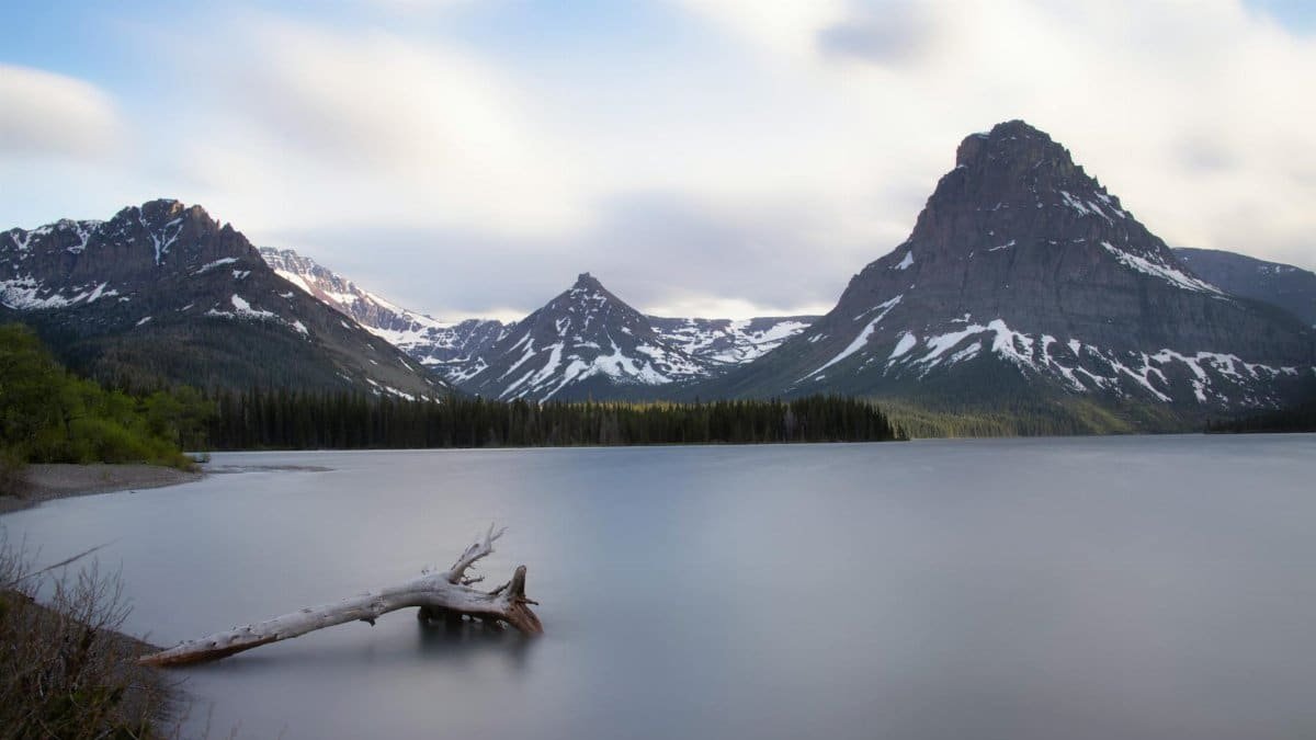 Serene lake with snow-capped mountains in Glacier National Park, Montana.